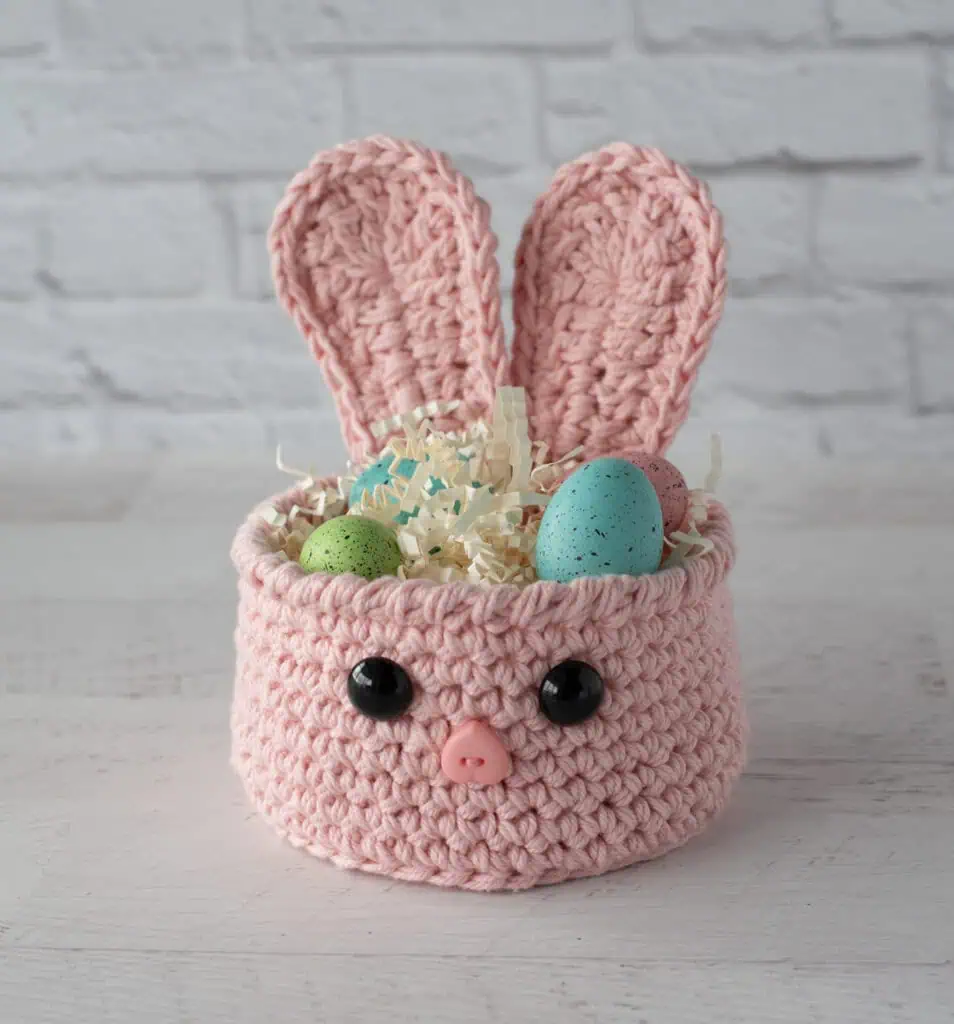 pink crochet bunny basket with decorative grass and Easter eggs