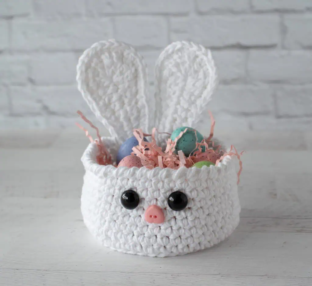 white crochet bunny basket with pink grass and Easter eggs