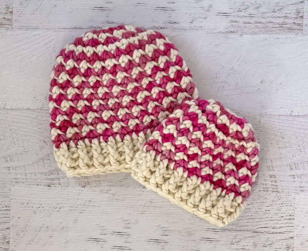 Colorful handmade crochet beanie hats on a whitewashed wood table