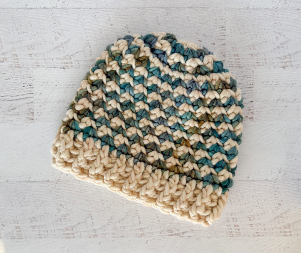 Colorful handmade crochet beanie hat on a whitewashed wood table