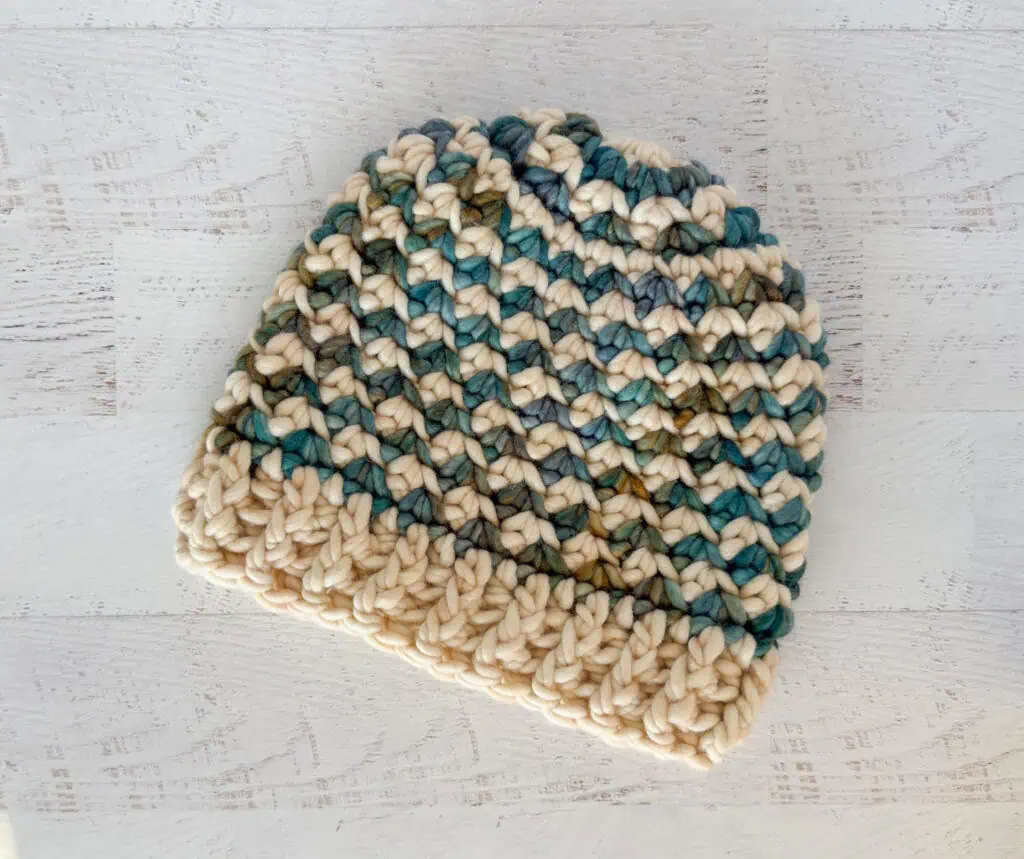 Colorful handmade crochet beanie hat on a whitewashed wood table