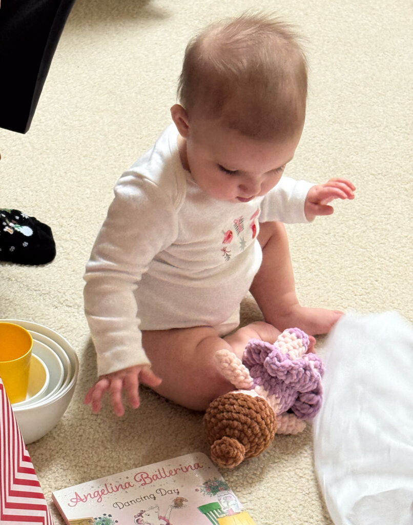 Baby on floor with toys, book and crochet ballerina doll