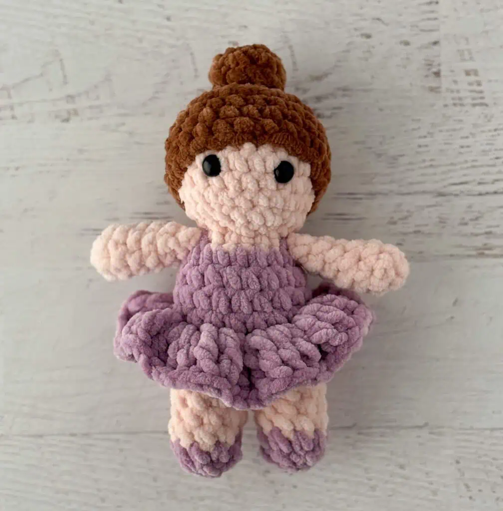 crochet ballerina with brown hair in purple dress on white wood table