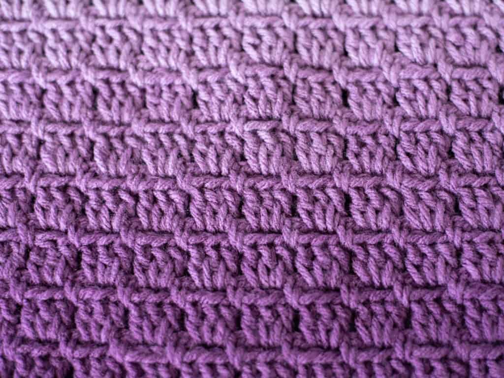 Close up of purple crochet baby afghan showing stitches