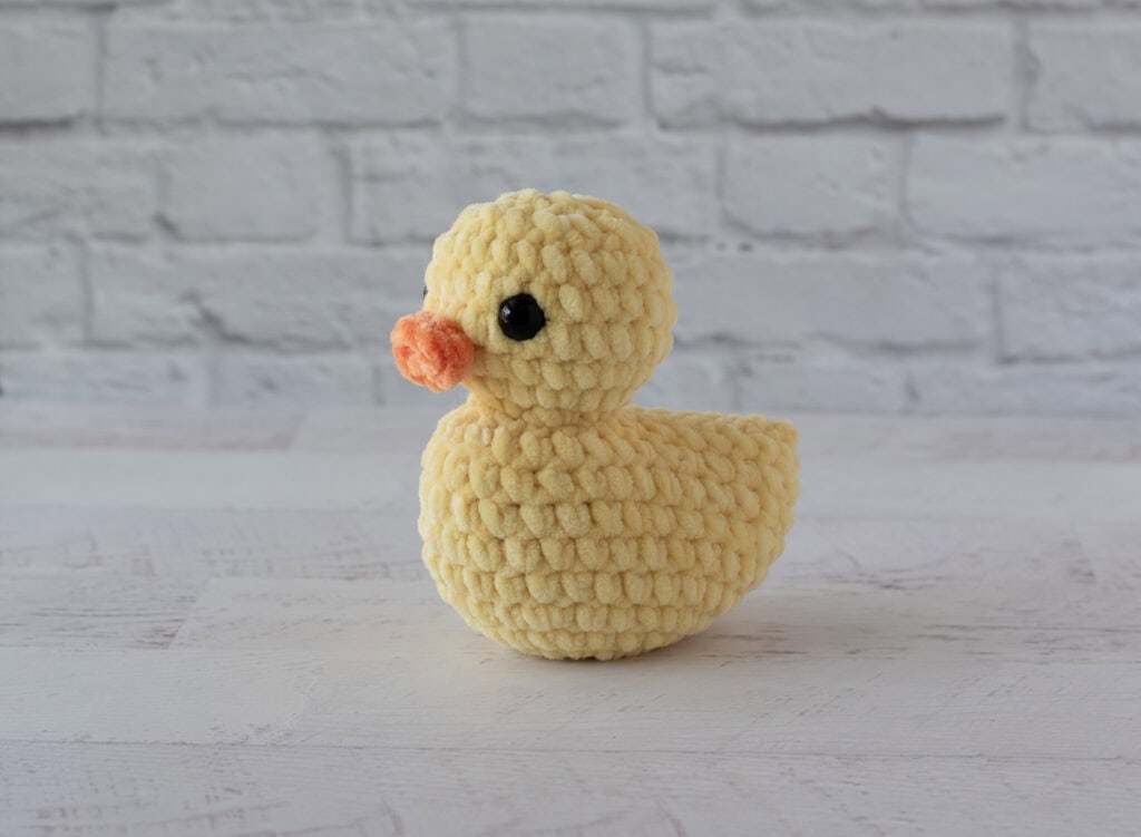 Yellow crochet duck on whitewashed wood table