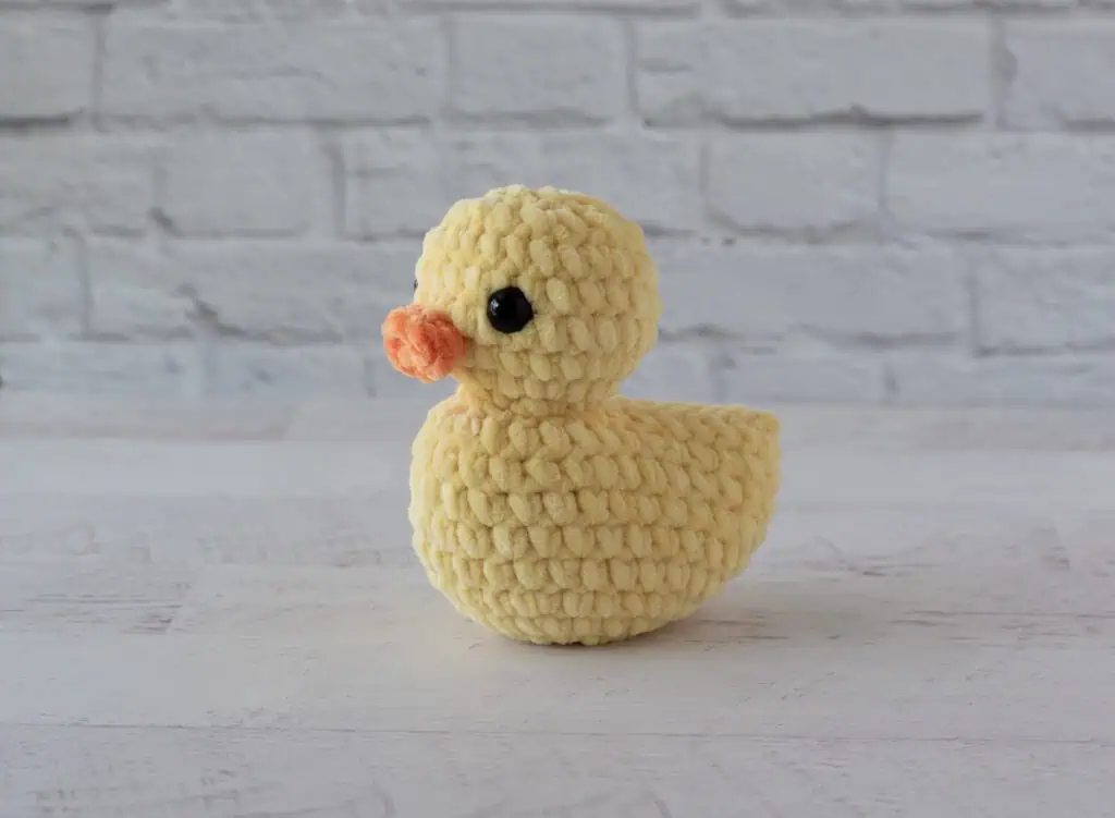Yellow crochet duck on whitewashed wood table
