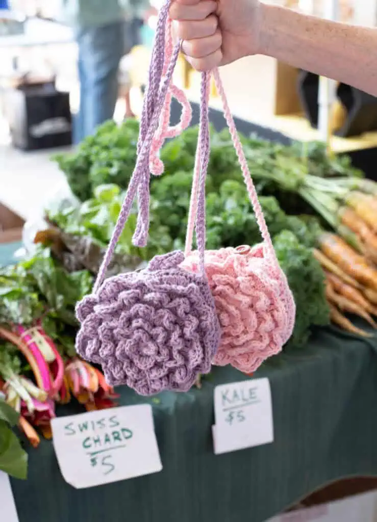 Purple and Pink crochet market bags in front of produce at a market