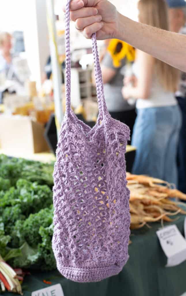 crochet market bag in front of produce at a market