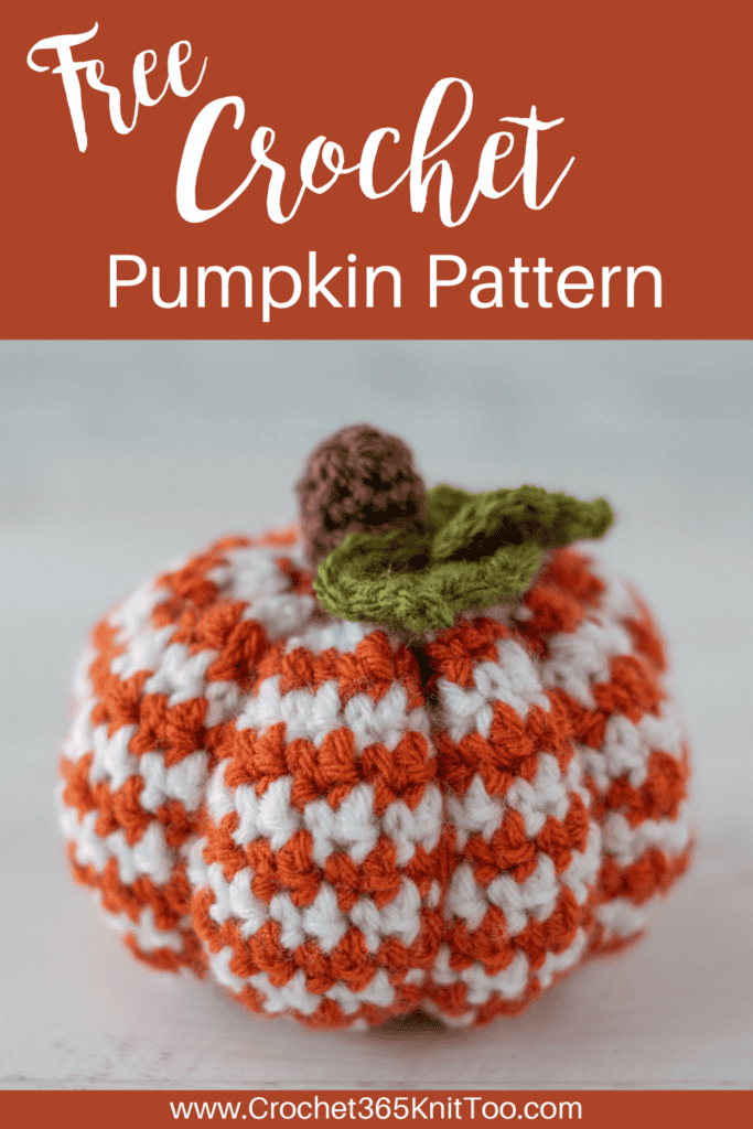 Image of crochet houndstooth patterned pumpkin in orange and white yarn with brown stem and green leaves
