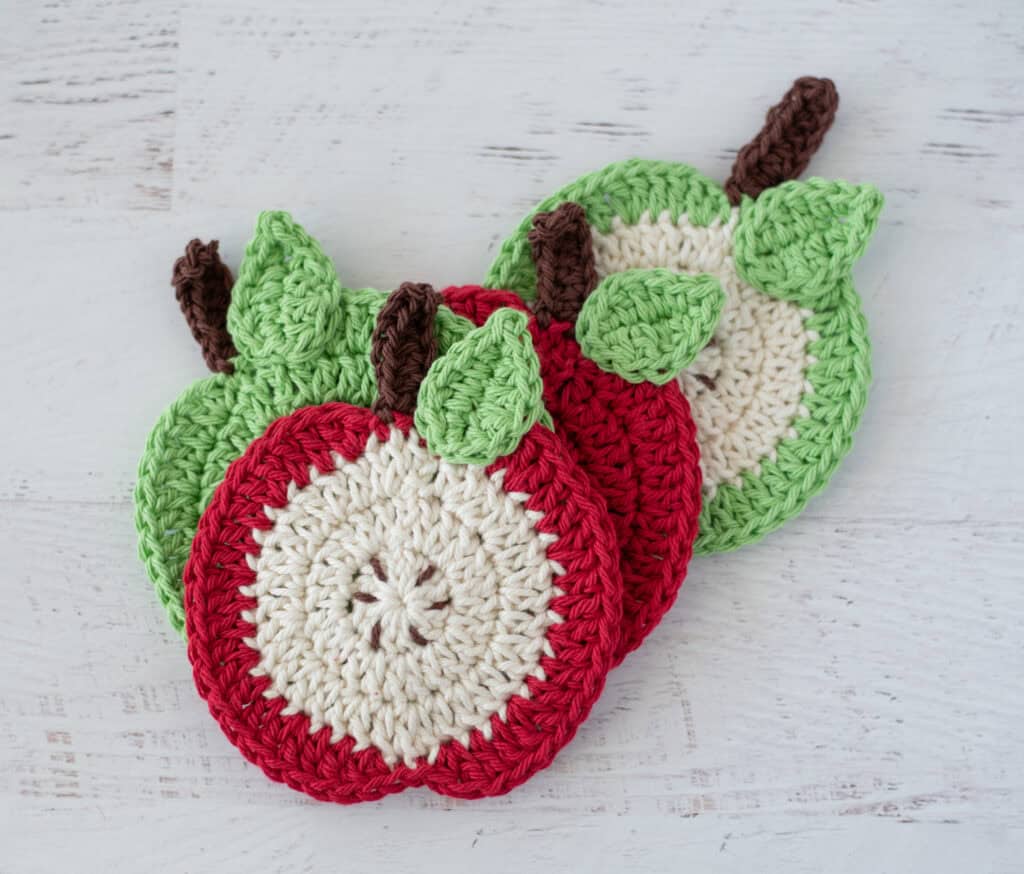 Crochet apple coasters in red, green and cream yarn
