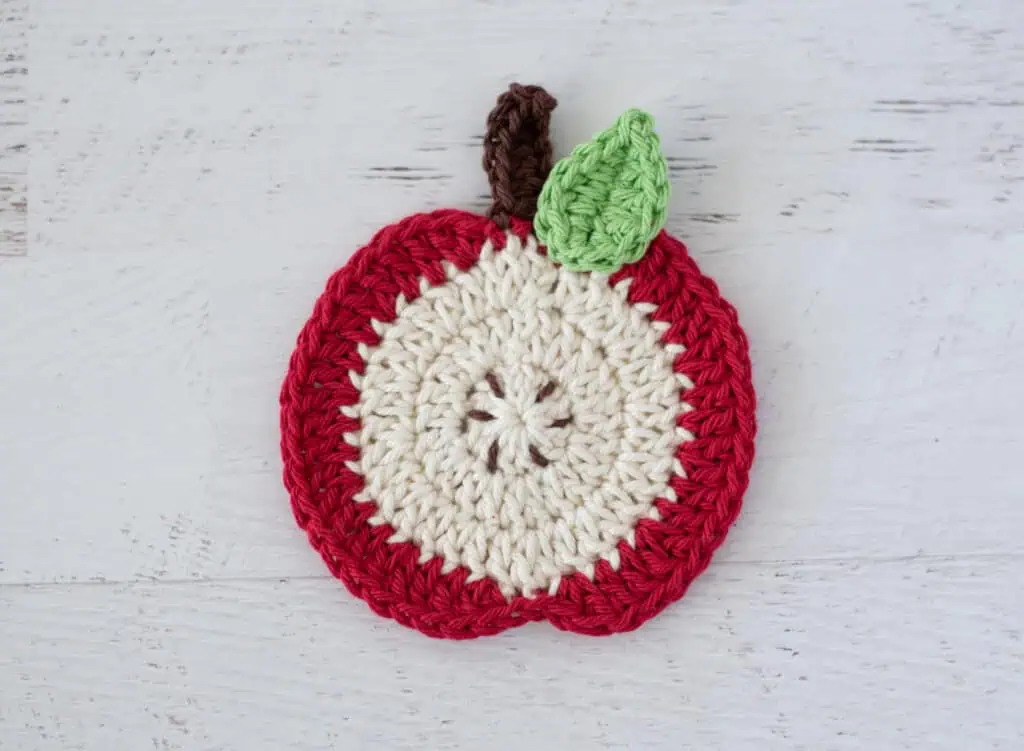 Red slice apple coaster in red and cream with brown stem and leaf.